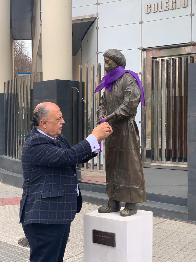 El Dr. Pedro Hidalgo adorna la estatua conmemorativa a la profesion medica con los simbolos del Dia de la Mujer