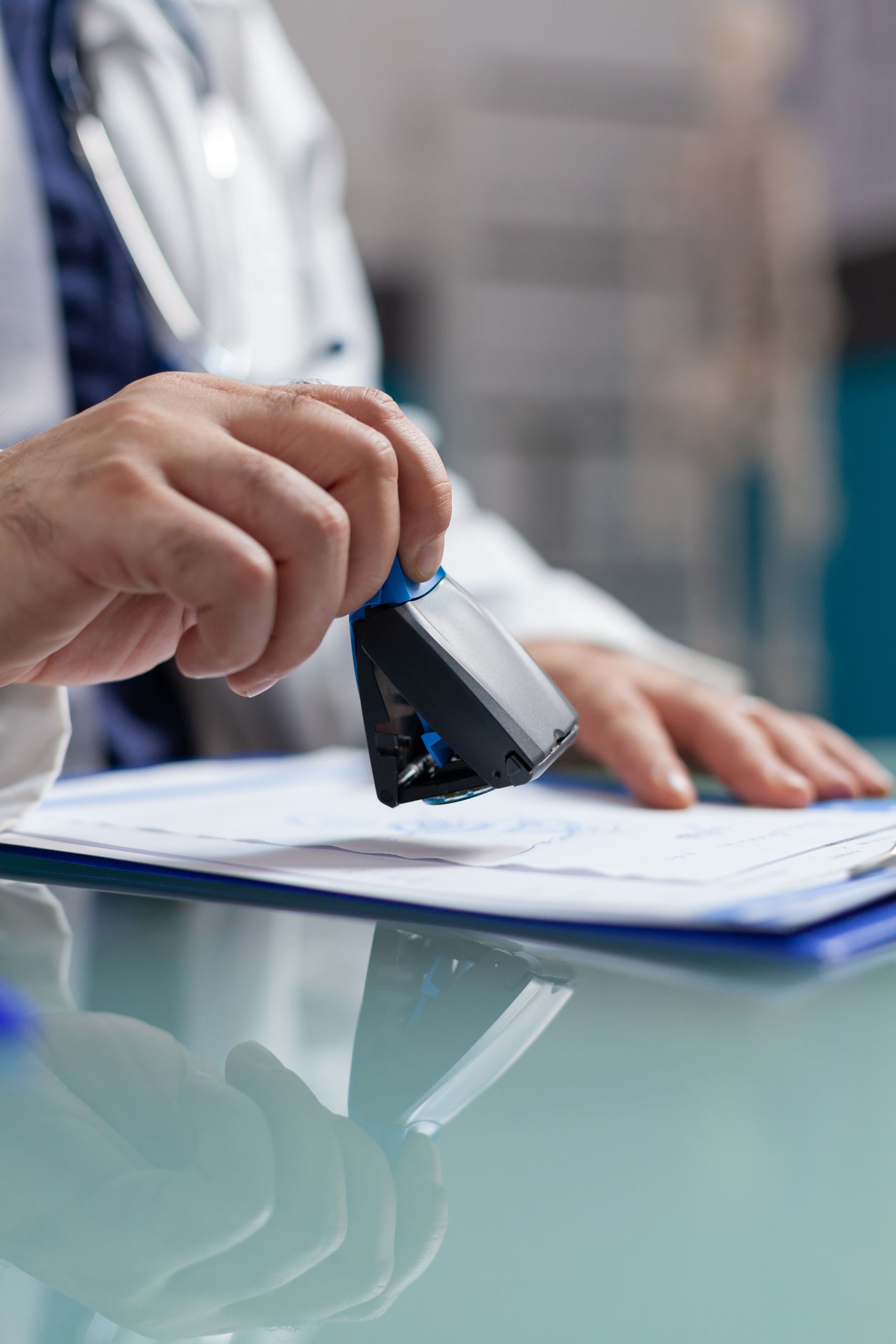 doctor holding medical stamp put prescription paper health care exam hand physician putting seal checkup report giving medicine patient consultation close up 1 scaled