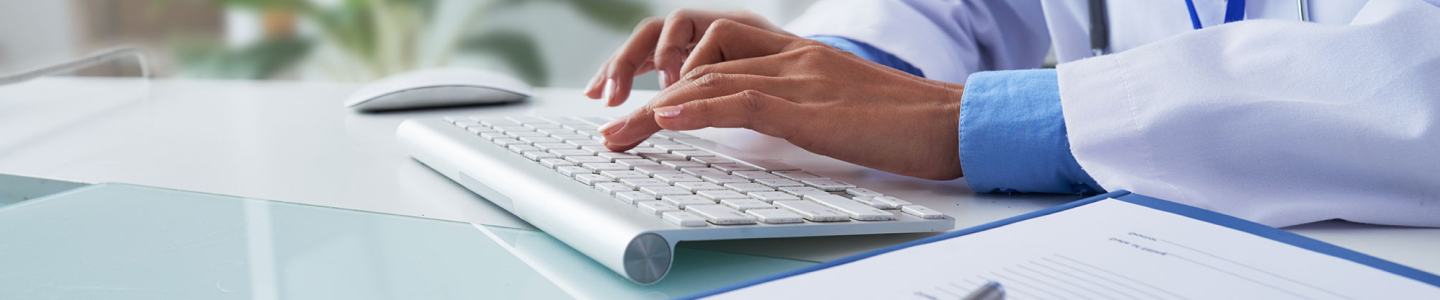 hands of unrecognizable female doctor typing on keyboard in office