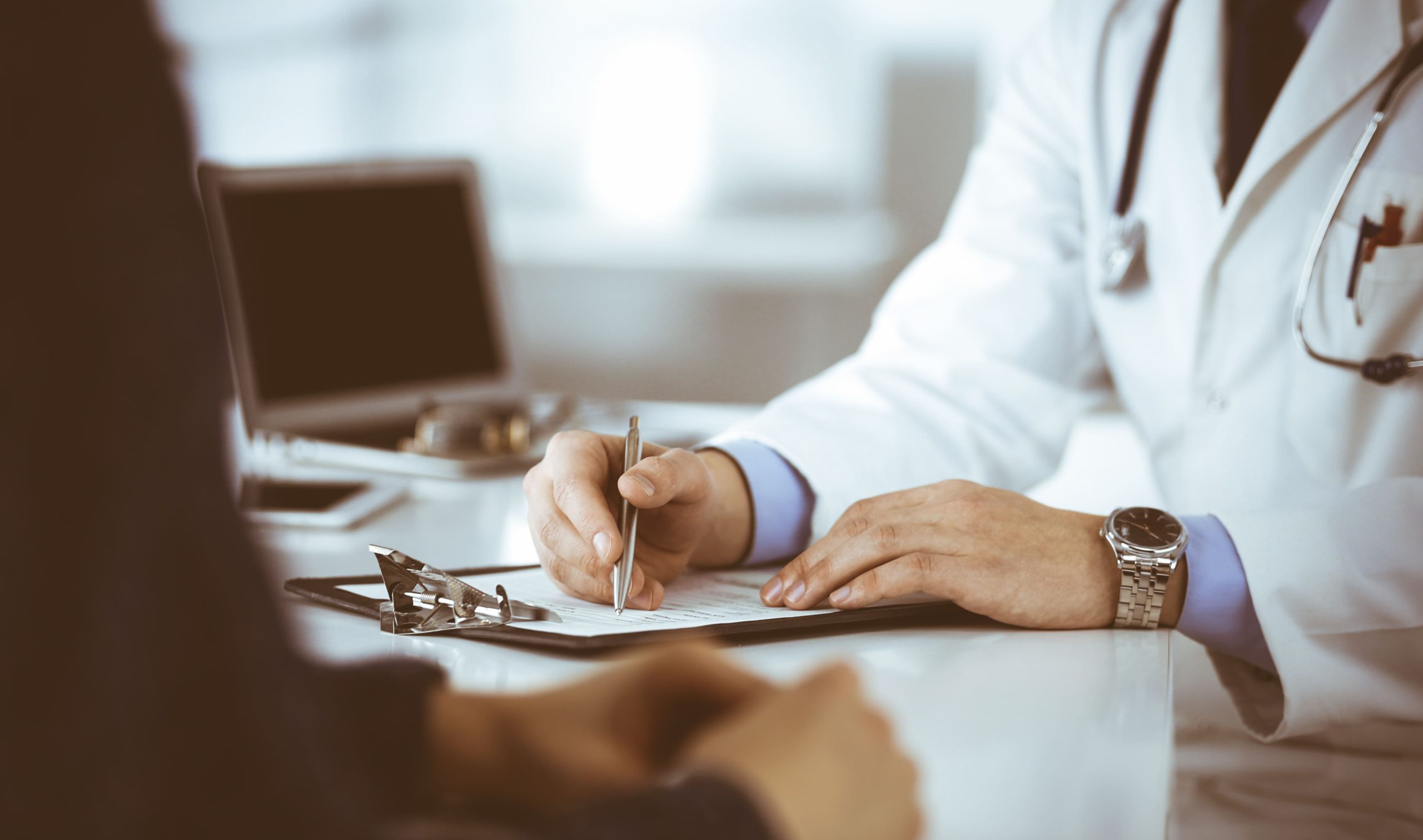 unknown young woman patient discuss results her medical tests with doctor while sitting desk hospital office physician using clipboard filling up medication history records 1 scaled